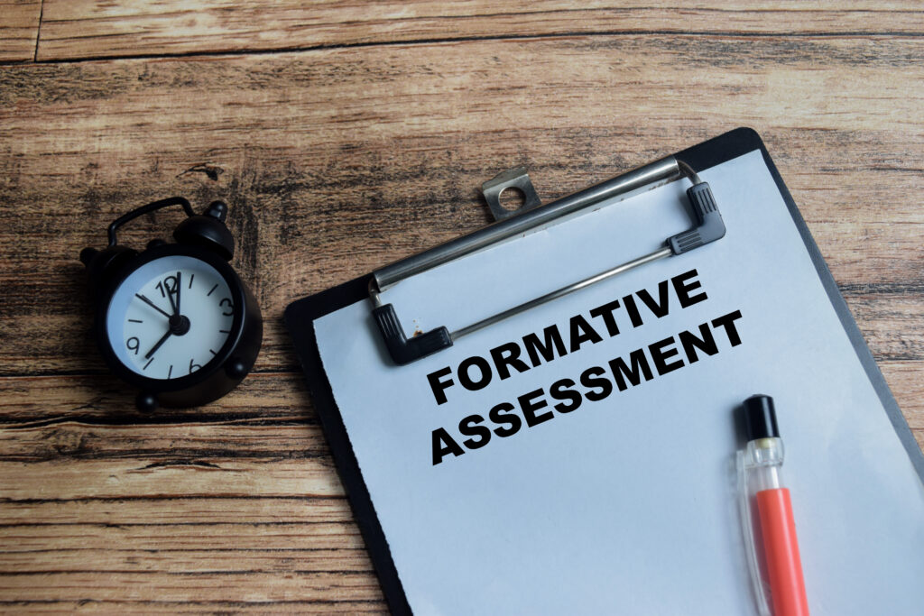 concept of formative assessment write on clipboard isolated on wooden table.